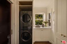 a washer and dryer in a small room next to a window with potted plants