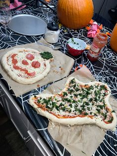 two pizzas sitting on top of paper towels next to pumpkins and other food