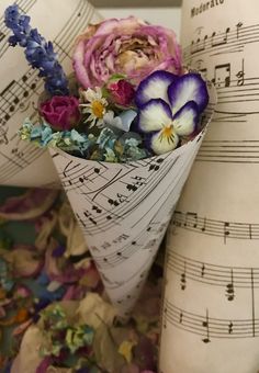 an arrangement of flowers in a cone with sheet music notes