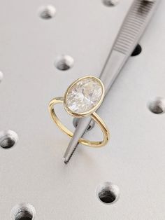 a close up of a ring with a diamond on it and a metal object in the background