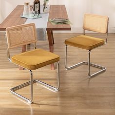 two chairs sitting on top of a hard wood floor next to a wooden dining table