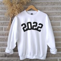 2022 Year Number Sweatshirt, 2022 Happy New Year Sweater, New Years Eve Top, 2022 Shirt, New Year Party Shirt, New Year Gift, Hello 2022 Shirt This gorgeous soft sweatshirt is a unisex style jumper so suitable for men or women.  Please reference the listing picture for sizing measurements. It's recommended to measure against an existing jumper or sweatshirt. Please refer to the delivery information for production time. I am based in Scotland however partner with printers from US and UK so if you live in the United States your order will come from there and normally sent standard USPS post. Unfortunately, the printers do not offer expedited shipping. As the order comes directly from printers I am unable to offer personalized messages to be included with your order. UNFORTUNATELY, ONCE YOU H New Years Eve Tops, Sasquatch Shirt, Birthday Sweater, 54th Birthday, 30th Birthday Shirts, 40th Birthday Shirts, Number Shirt, Birthday Gift For Women, Birth Year