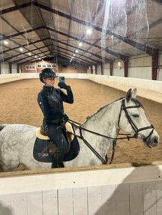 a woman riding on the back of a white horse