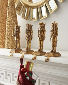 a christmas stocking hanging from a mantel in front of a mirror with gold statues on it