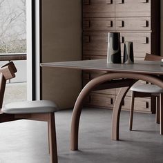 a wooden table with two chairs and a vase on it in front of a window