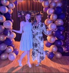 two women standing in front of balloons on a stage