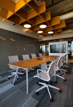 an empty conference room with chairs and a flat screen tv on the wall above it