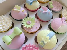 a box filled with lots of cupcakes covered in fondant and decorated to look like baby's first birthday