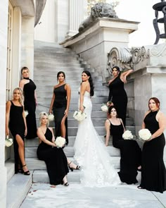 a group of women in black dresses posing for a photo on the steps of a building