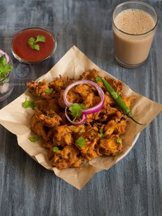 some food is sitting on a table next to a glass of juice and another drink