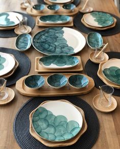 a wooden table topped with plates and bowls filled with green leafy designs on them