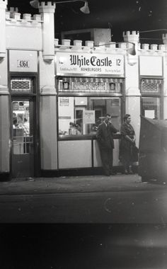 an old photo of two men standing in front of a white castle convenience store at night