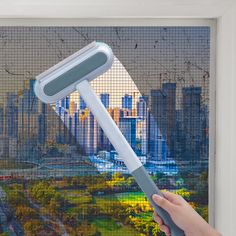 a person is holding a brush in front of a window with a cityscape behind it