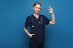 a woman in scrubs is making the peace sign with her hand and wearing a stethoscope