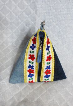 a small purse is hanging on the side of a white cloth bag with blue and red flowers