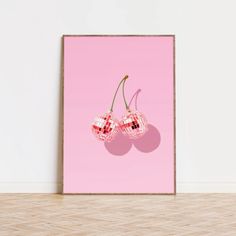 two cherries on a pink background in front of a white wall