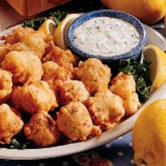 a white plate topped with tater tots next to lemon wedges and dip