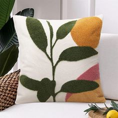 a decorative pillow on a white couch next to a potted plant