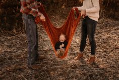 a baby in a hammock being held by two adults