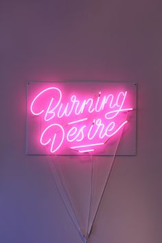 a neon sign that says burning desire on the side of a wall in a room