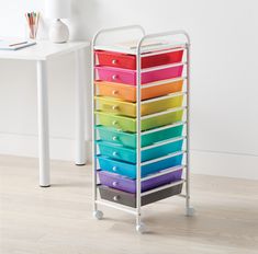 a multicolored drawer cart with six drawers on it and a white table in the background