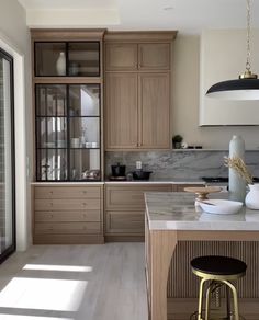 a kitchen with wooden cabinets and marble counter tops, two stools in front of the island