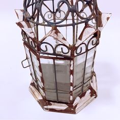 an old stained glass lantern with wrought iron work on the top and sides, sitting on a white surface