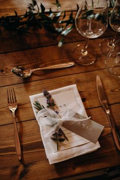 place setting with napkins, silverware and flowers on wooden table top next to utensils