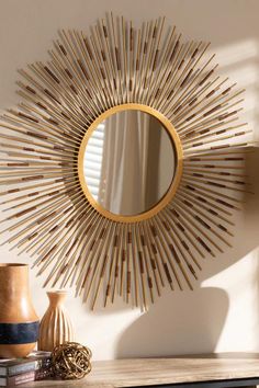 a mirror sitting on top of a wooden table next to a vase and other items