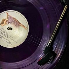 a purple record with a black sticker on it sitting next to a pair of scissors