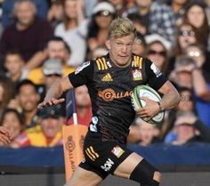 a man running with a rugby ball in his hand and people watching from the stands