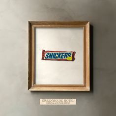 a framed candy bar sticker on the wall above a sign that says snickkers