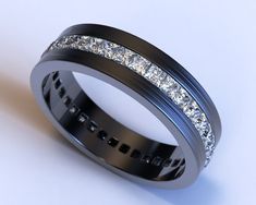 a wedding band with diamonds is shown on a white surface, the ring has black and silver inlays