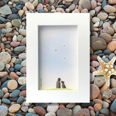 a starfish is sitting on some rocks next to a white frame with a couple in it