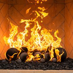 a fire is burning in an outdoor fireplace with rocks and stones around it, as well as flames