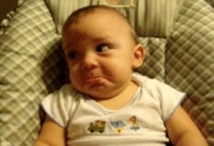 a baby sitting in a chair looking at the camera with an angry look on his face