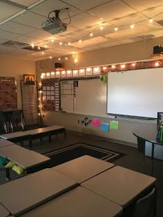 an empty classroom with desks, chairs and a projector screen in the center