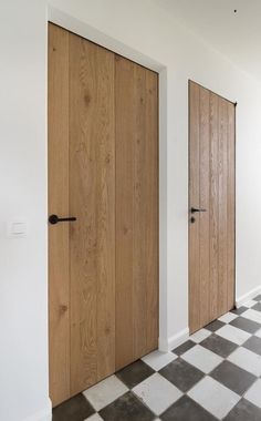 two wooden doors in an empty room with checkered flooring on the ground and white walls