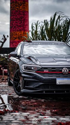 a black car parked in front of a tall red building on a rainy day with its hood up