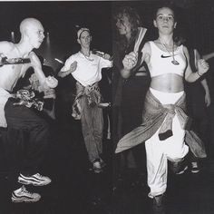 black and white photograph of people dancing at a dance party with one man holding a bat