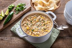 a white pot filled with corn and salsa next to some tortilla chips