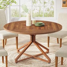 a round wooden table with four chairs around it and a vase on the table top