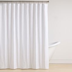 a white shower curtain hanging on the side of a bath tub