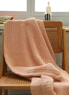 a pink blanket sitting on top of a wooden chair