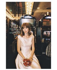 a woman in a white dress sitting on a chair next to a slot machine at a casino