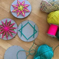 three circular pieces of paper with yarn on the floor next to them and some balls of thread