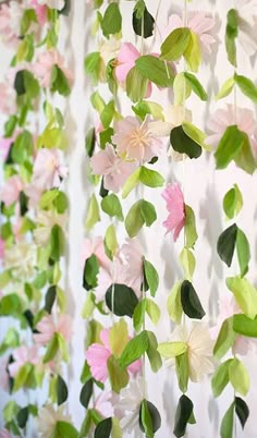 some pink and green flowers are hanging on the wall