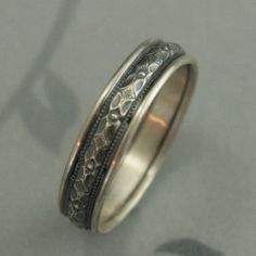 a wedding ring with filigrees is shown on a gray surface, and has an intricate design in the middle