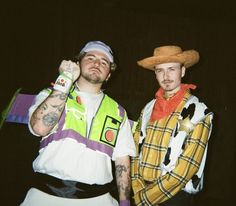 two men dressed in costumes standing next to each other with one holding a beer bottle