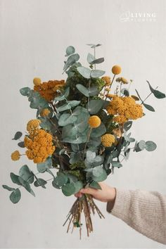 a person holding a bunch of flowers in their hand with leaves on it and the words living above them